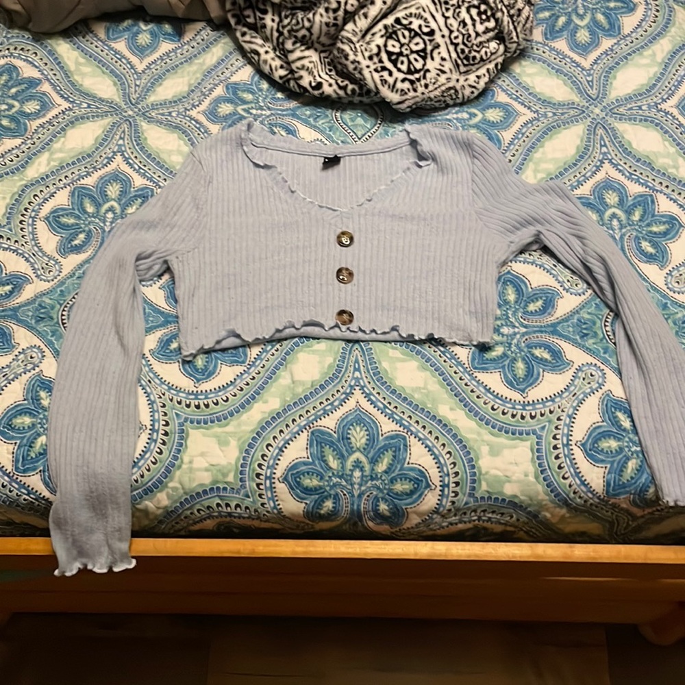 A cropped, baby blue sweater with false buttons